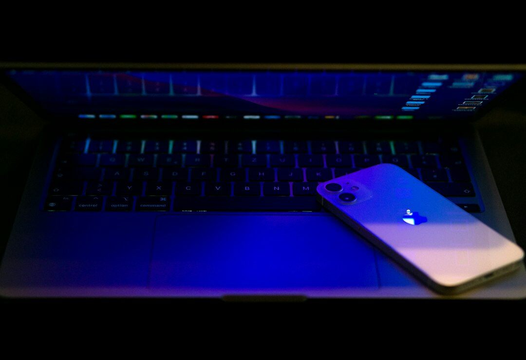 Smartphone next to a laptop showing app code