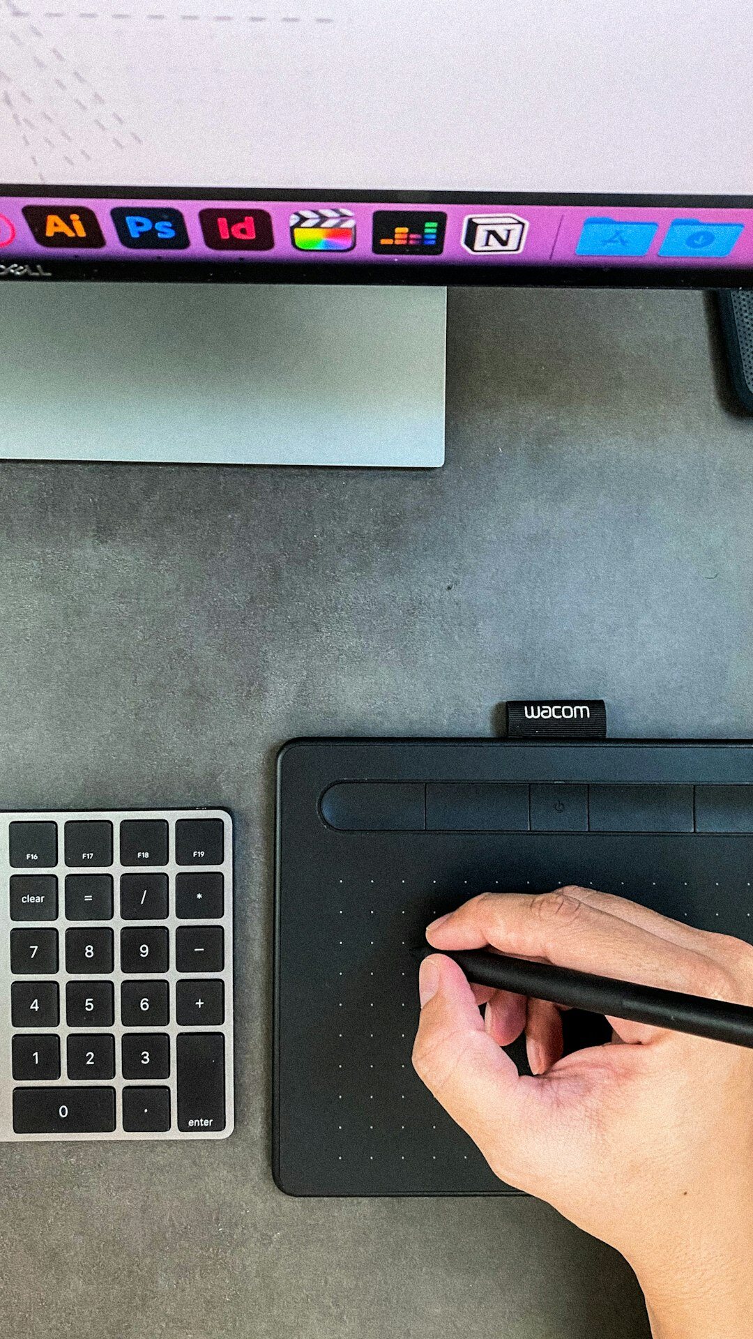 Designer sketching a mobile app wireframe on a tablet next to a monitor